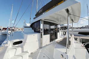 Eine Yacht mit einem 'BALI' Schild, einer überdachten Sitzgelegenheit und Blick auf den Hafen.