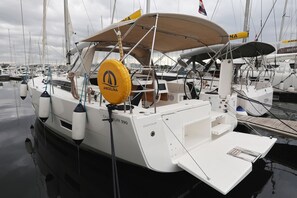 A sailboat docked at a marina with multiple boats, a covered deck, and a name 'DUFOUR 390' visible. - Sun-kissed Sailing Adventure in Split-Dalmatia, Croatia (Trogir)