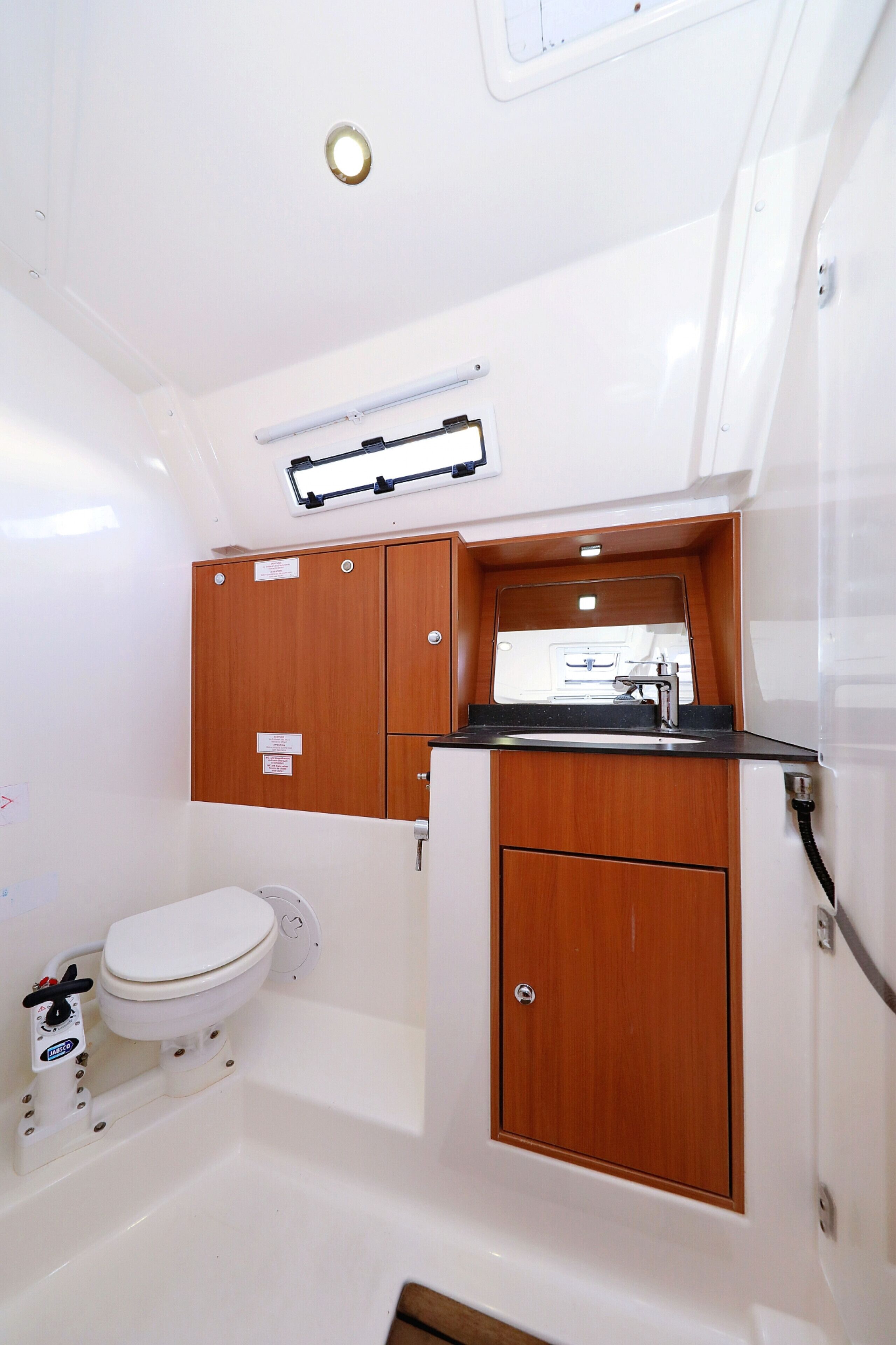 A compact bathroom with a toilet, a sink, and wooden cabinets.