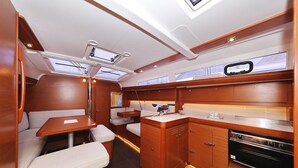 A compact, well-lit interior with a kitchenette, seating area, and a small table. - Sun-kissed Sailing Adventure in Split-Dalmatia, Croatia (Trogir)