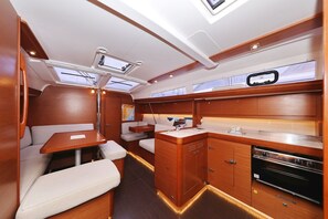 A compact, well-lit interior with a kitchenette, seating area, and a small table. - Sun-kissed Sailing Adventure in Split-Dalmatia, Croatia (Trogir)