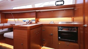 A compact kitchen with wooden cabinetry, a built-in oven, and a small dining area with a bench. - Sun-kissed Sailing Adventure in Split-Dalmatia, Croatia (Trogir)