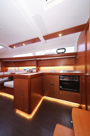 A compact kitchen with wooden cabinetry, a built-in oven, and a small dining area with a bench. - Sun-kissed Sailing Adventure in Split-Dalmatia, Croatia (Trogir)