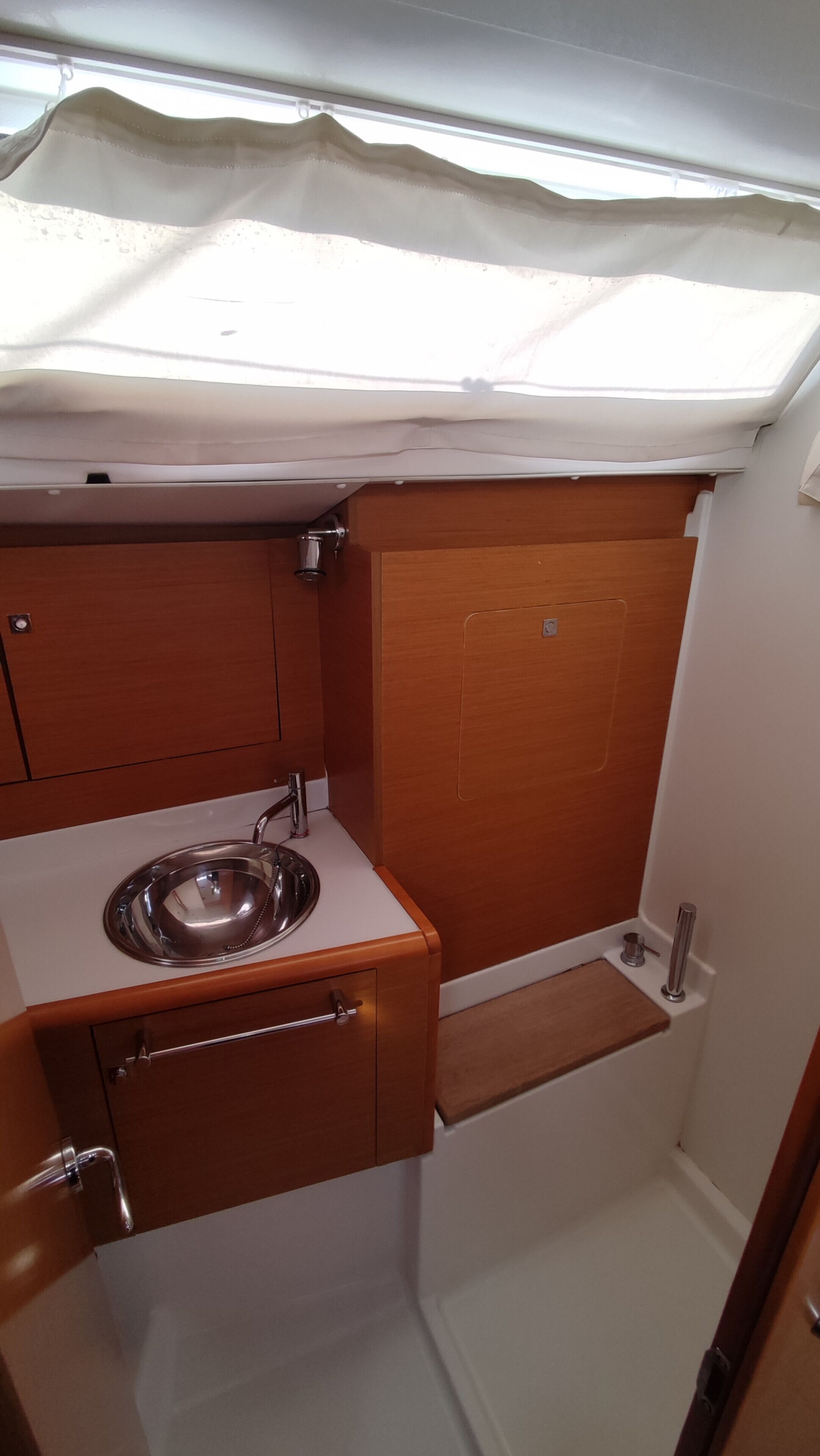 Una kitchenette compacta con un lavamanos, armarios de madera y una pequeña encimera.