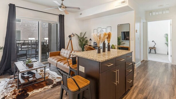 A modern kitchen with a central island, a dining area with a leather sofa, and a large window with a view of the outdoors. - Quiet condo w/ balcony, fast Wi‑Fi & gym (Salt Lake City)