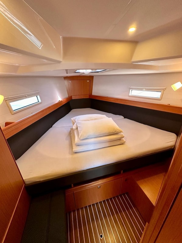 Ein kleines, gemütliches Abteil mit Bett, Stauraumschränken und einem kleinen Fenster.