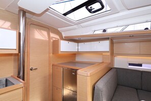 A compact interior with a kitchenette, a cushioned seating area, and a skylight. - Sibenik Sun and Beach Sailing Extravaganza: A Croatian Coastal Adventure (Vodice)