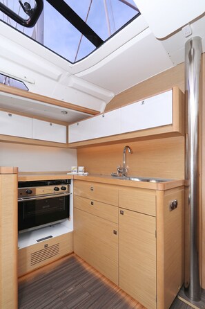 A compact kitchen with a built-in oven, a sink, and wooden cabinetry. - Sibenik Sun and Beach Sailing Extravaganza: A Croatian Coastal Adventure (Vodice)
