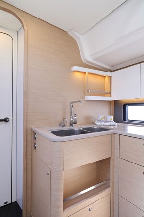 A compact kitchen with a sink, cabinets, and a window. - Sun-Kissed Sailing Adventure in Istria, Croatia (Pula)