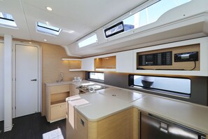 A compact kitchen with built-in appliances, a window for natural light, and a control panel above the stove. - Sun-Kissed Sailing Adventure in Istria, Croatia (Pula)