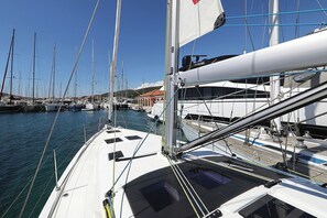 Ein Yachthafen mit mehreren Segelbooten, ein klarer Himmel und ein Gebäude mit rotem Dach im Hintergrund.
