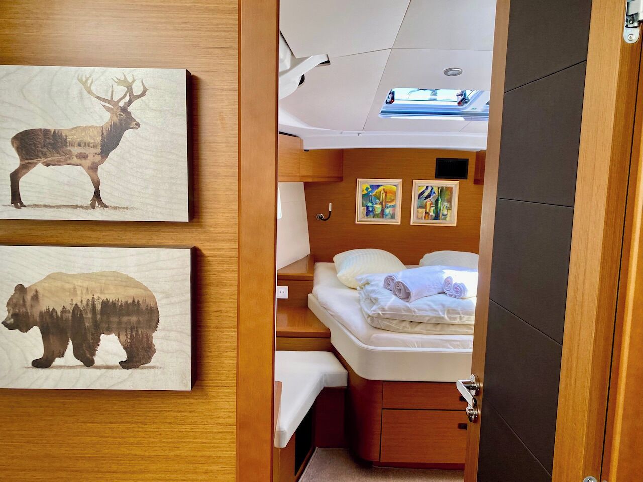 Een kleine kamer met een bed, nachtkastje, wandlamp en kunst met dieren.