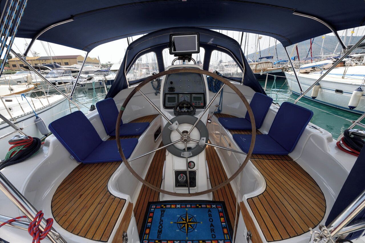 Cubierta de barco con timón, panel de control y asientos azules.