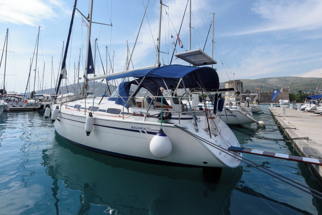 Un puerto deportivo con varios veleros amarrados, que cuenta con una cubierta techada y un panel solar.