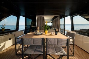 Een eethoek met een tafel, stoelen, een potplant en uitzicht op het water.