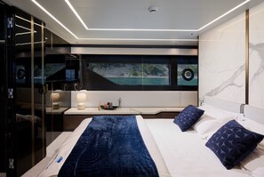 Een moderne hotelkamer met een bed, nachtkastje, lamp en uitzicht door het raam.