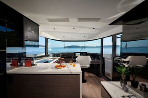 Eine moderne Küche mit einer großen Kochinsel, einem Essbereich und Blick auf das Meer.