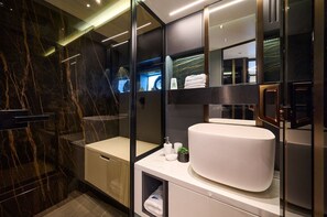 Een moderne badkamer met een marmeren wand, een grote wastafel en een spiegel.