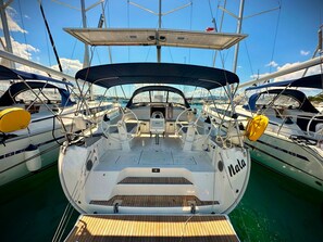 Uma marina com vários veleiros atracados, destacando um barco central com leme, toldo e o nome 'Nala' na lateral.