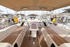 A boat deck with a central table, seating areas, and a steering wheel. - Sun-kissed Sailing Adventure in Split-Dalmatia, Croatia (Trogir)