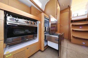 Eine kompakte Küche mit Einbauofen, Kühlschrank, Holzausstattung und einem Fenster.