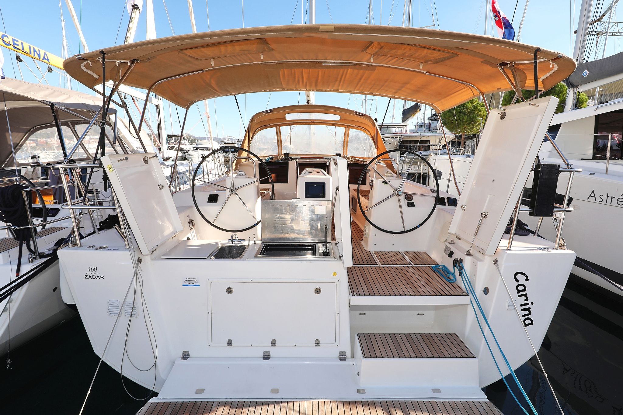 A yacht with a covered deck, a steering wheel, and a name 'Carina' on the side.