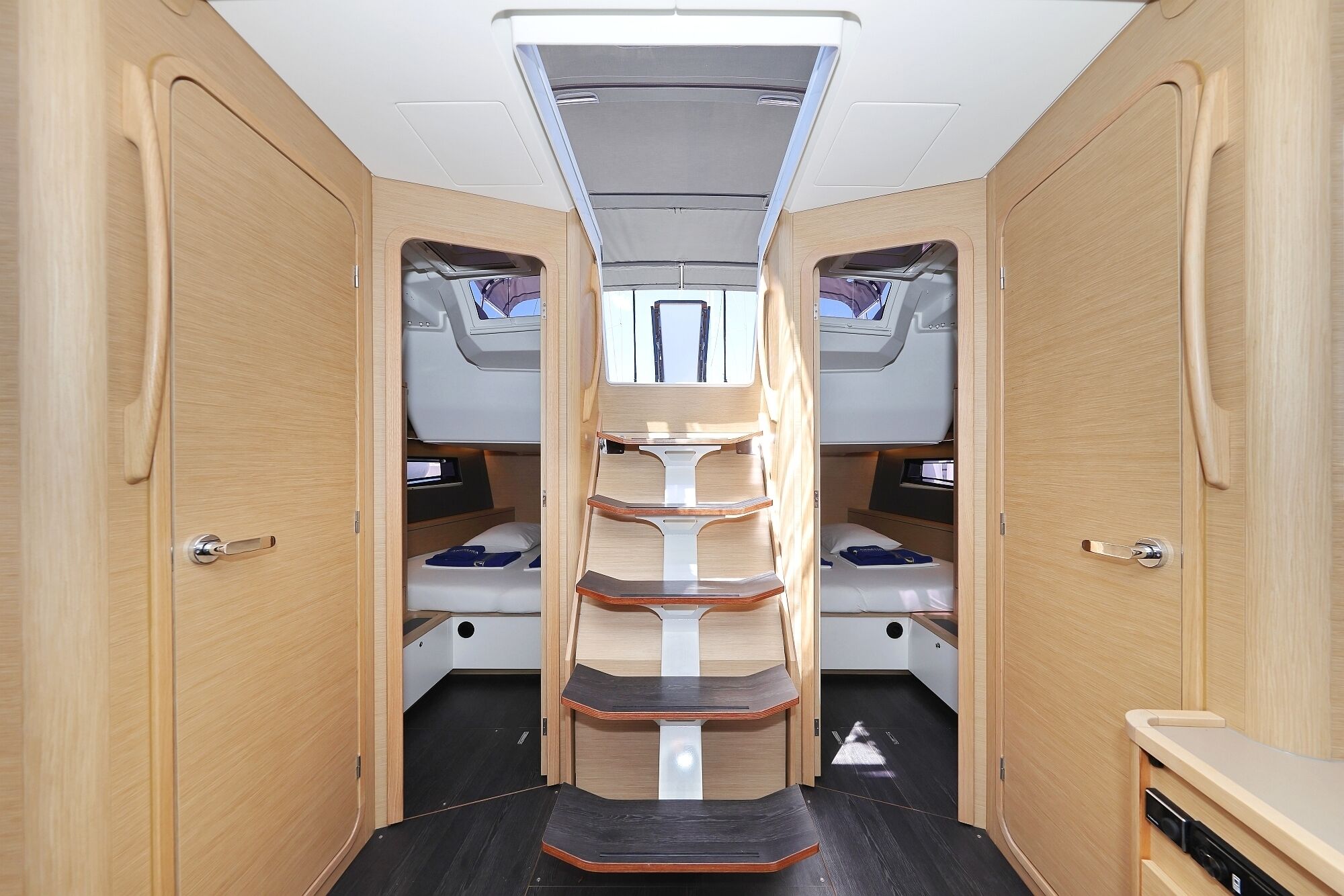Interior compacto de autocaravana con pasillo central, dos literas a cada lado y una pequeña zona de kitchenette.