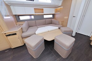 A compact RV interior with a sofa bed, two cushioned seating areas, a small table, and storage cabinets. - Sun-kissed Sailing Adventure in Split-Dalmatia, Croatia (Trogir)