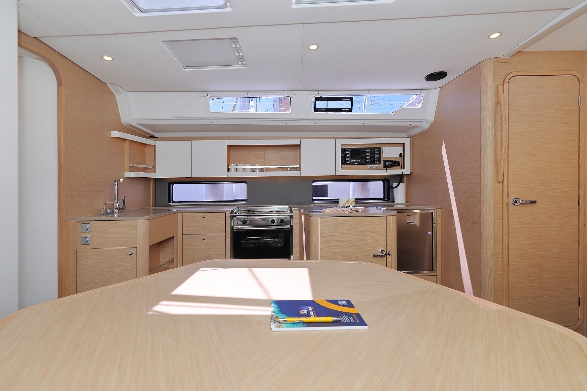 A compact kitchen with a microwave, stove, and sink, and a door with a handle.