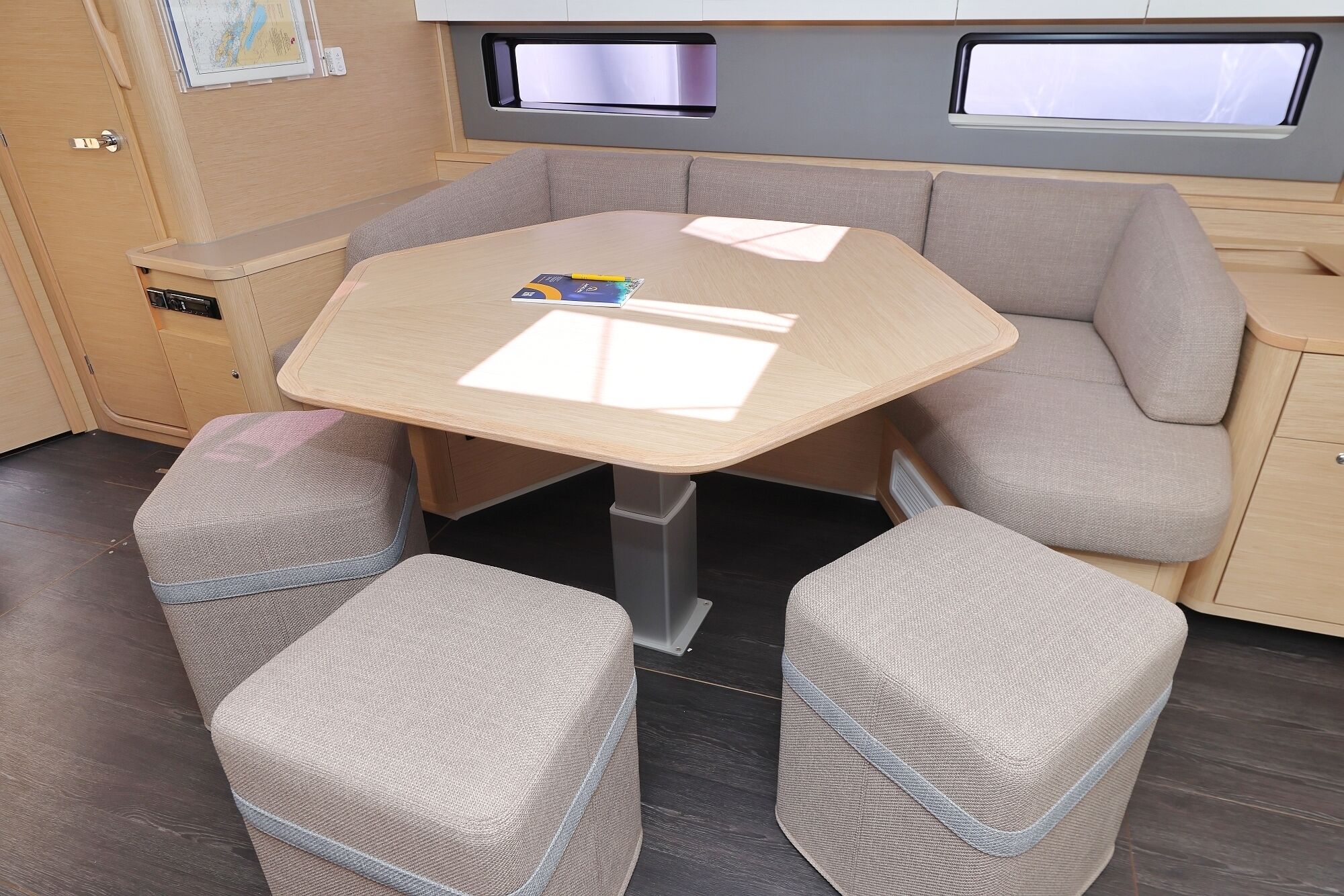 A compact kitchenette with a small table, two cushioned seating areas, and a window above the sink.
