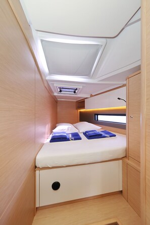 Cabine compacta e bem iluminada, com cama, armários de armazenamento e um claraboia.
