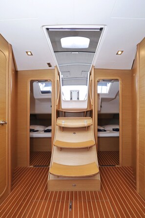 Een compact, goed verlicht interieur met een centrale zithoek, twee slaapplaatsen en een schuin dak.