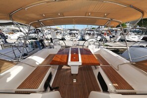 A boat deck with a central table, seating, and a canopy. - Sun-kissed Sailing Adventure in Split-Dalmatia, Croatia (Trogir)