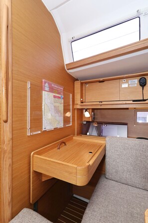 Ein kompaktes Wohnmobil-Interieur mit Holztisch, einer Karte, einer Lampe und einer gepolsterten Sitzecke.
