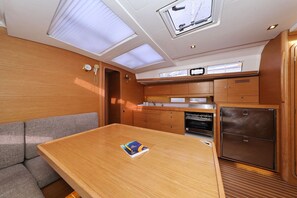 A compact kitchen with a wooden table, a built-in oven, and a refrigerator. - Sun-kissed Sailing Adventure in Split-Dalmatia, Croatia (Trogir)