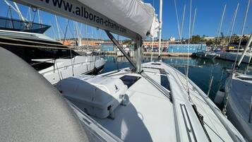 Un port de plaisance où sont amarrés de nombreux voiliers, une bannière de site web et un ciel bleu azur.