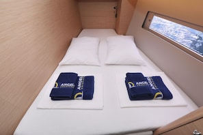 Une petite cabine comprenant un lit, deux oreillers et deux serviettes ornées d’un logo.