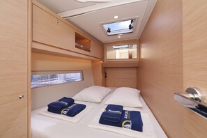 A compact cabin with a bunk bed, a skylight, a small window, and a mirror. - Sibenik Sun and Beach Sailing Extravaganza (Tribunj)