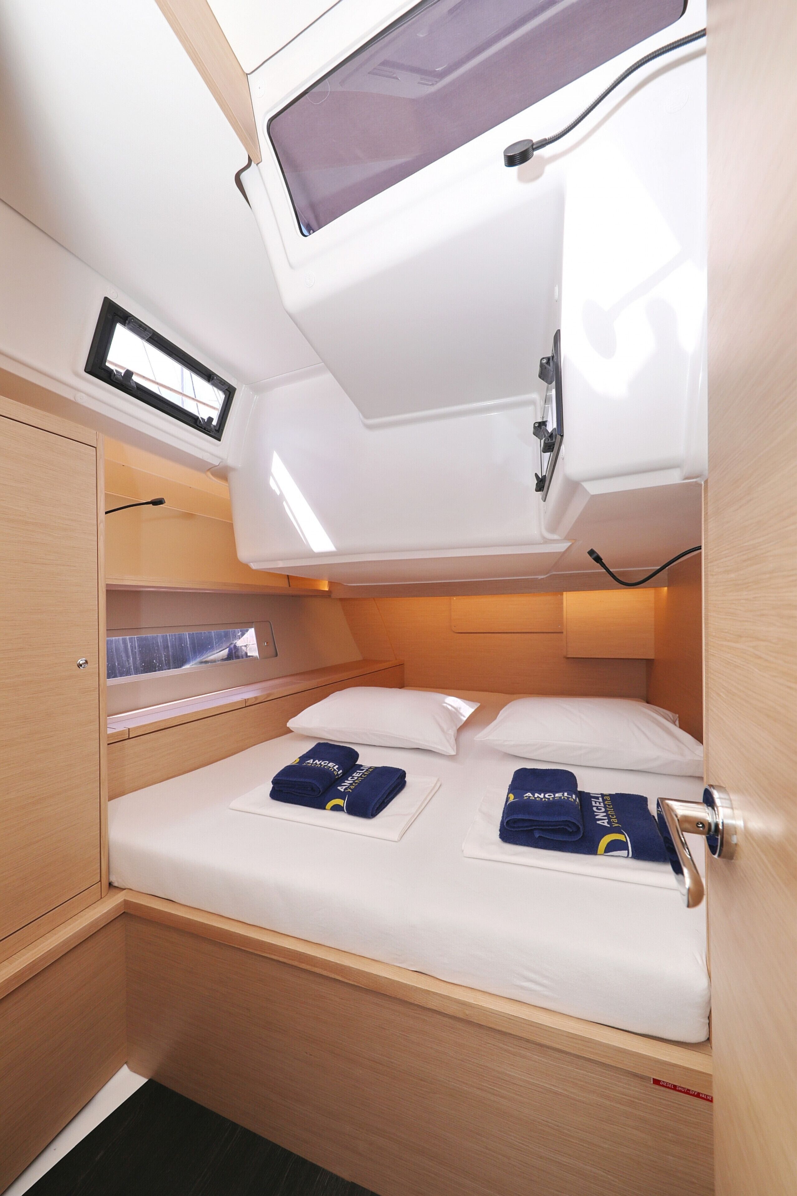 Une petite cabine équipée d’un lit superposé, d’une lucarne et d’une petite fenêtre.