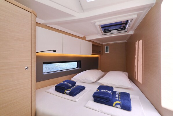 Quarto compacto com cama, janela e ar condicionado integrado.