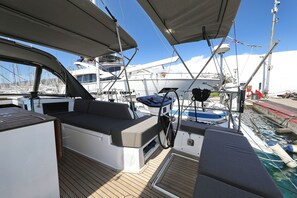 A yacht deck with a seating area, a steering wheel, and a water cooler. - Sibenik Sun and Beach Sailing Extravaganza (Tribunj)