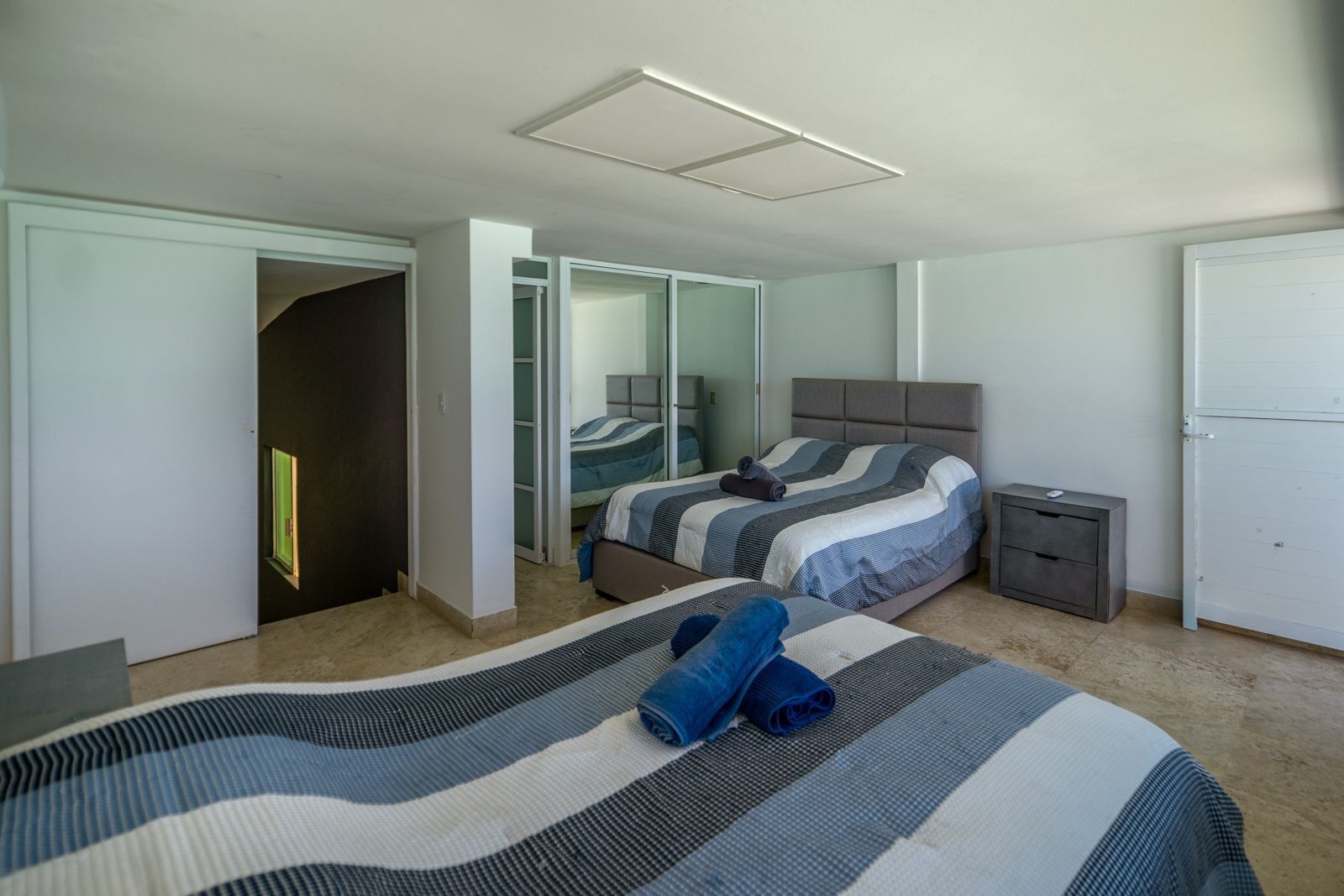 A bedroom with a bed, a nightstand, a wardrobe, and a door leading to another room.