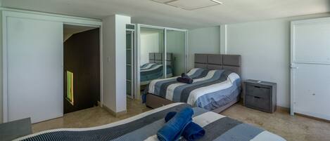 A bedroom with a bed, a nightstand, a wardrobe, and a door leading to another room.