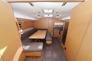 Interior compacto de RV com área de refeições, cozinha compacta e porta que dá para outro cômodo.