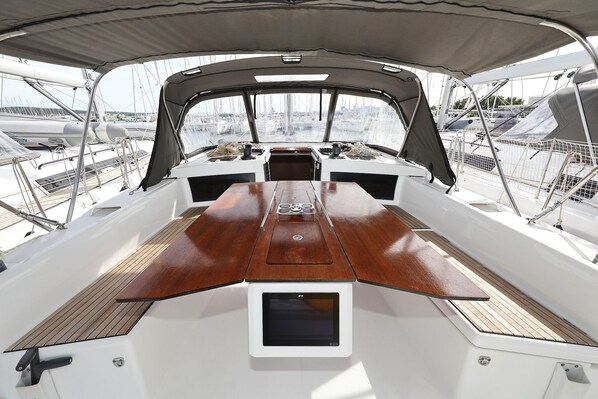 Ein Bootsdeck mit einem zentralen Tisch, Sitzgelegenheiten und Blick auf andere Boote.