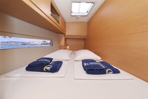 Ein kleines Zimmer mit einem Bett, zwei Handtüchern, einem Dachfenster und einem Fenster mit Blick auf eine Marina.