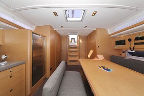A compact RV interior with a kitchenette, a dining area, and a sleeping berth. - Sun-Kissed Sailing Adventure in Zadar, Croatia (Bibinje)