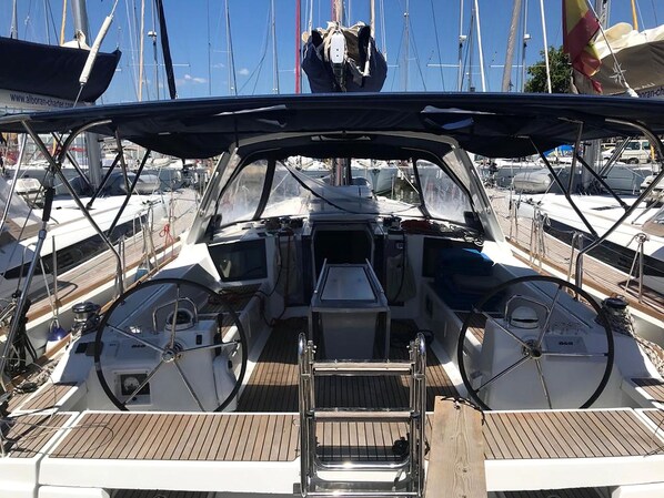 A boat deck with a central steering wheel, a small table, and a seating area.