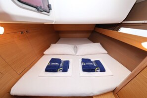 Ein kleines Zimmer mit einem Einzelbett, zwei Kissen und zwei Handtüchern mit einem Logo.