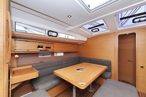 A compact interior with a table, bench seating, overhead storage, and a door. - Sun-kissed Sailing Adventure in Split-Dalmatia, Croatia (Trogir)